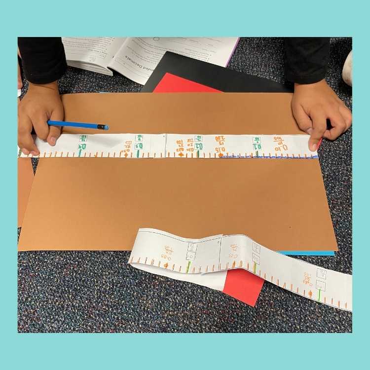 Using meter tape to measure paper to teach decimals