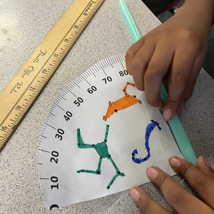 Student taping a straw to astrolabe craft